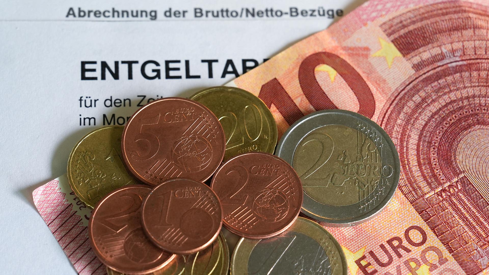 Euro- und Centmünzen liegen auf einem 10-Euro-Schein und einer Entgeltabrechnung. | dpa