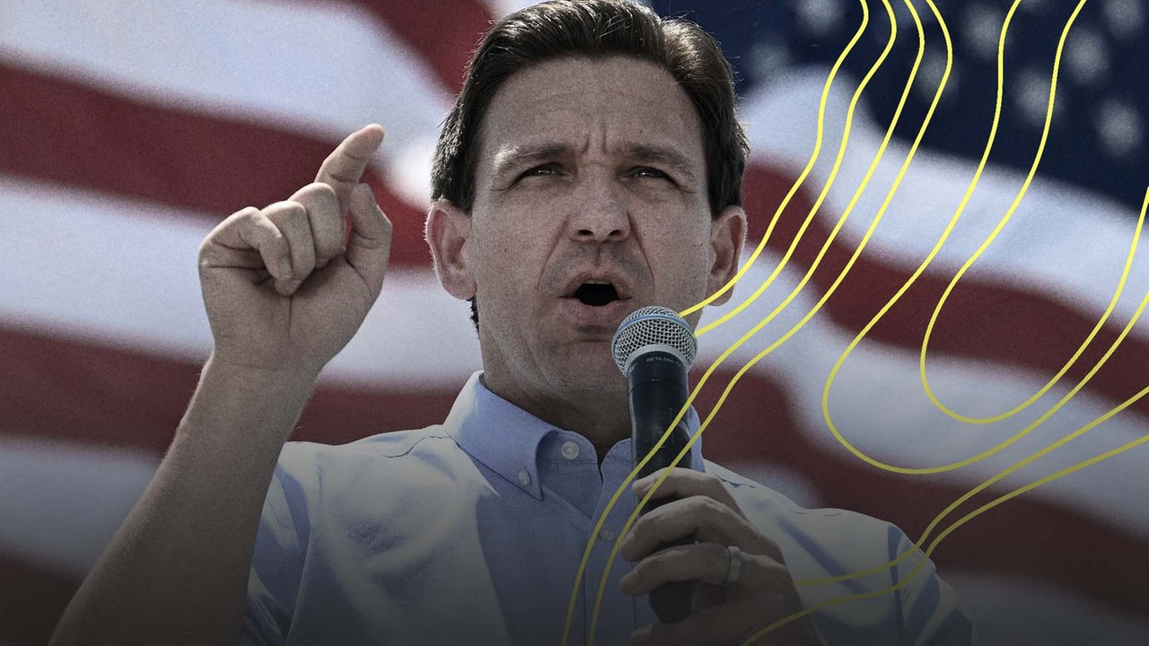 Der Gouverneur von Florida, Ron DeSantis, steht vor der amerikanischen Flagge und spricht in ein Mikrofon. Er hält seinen Zeigefinger in die Luft | picture-alliance/ dpa/ AP Foto: Andy Barron