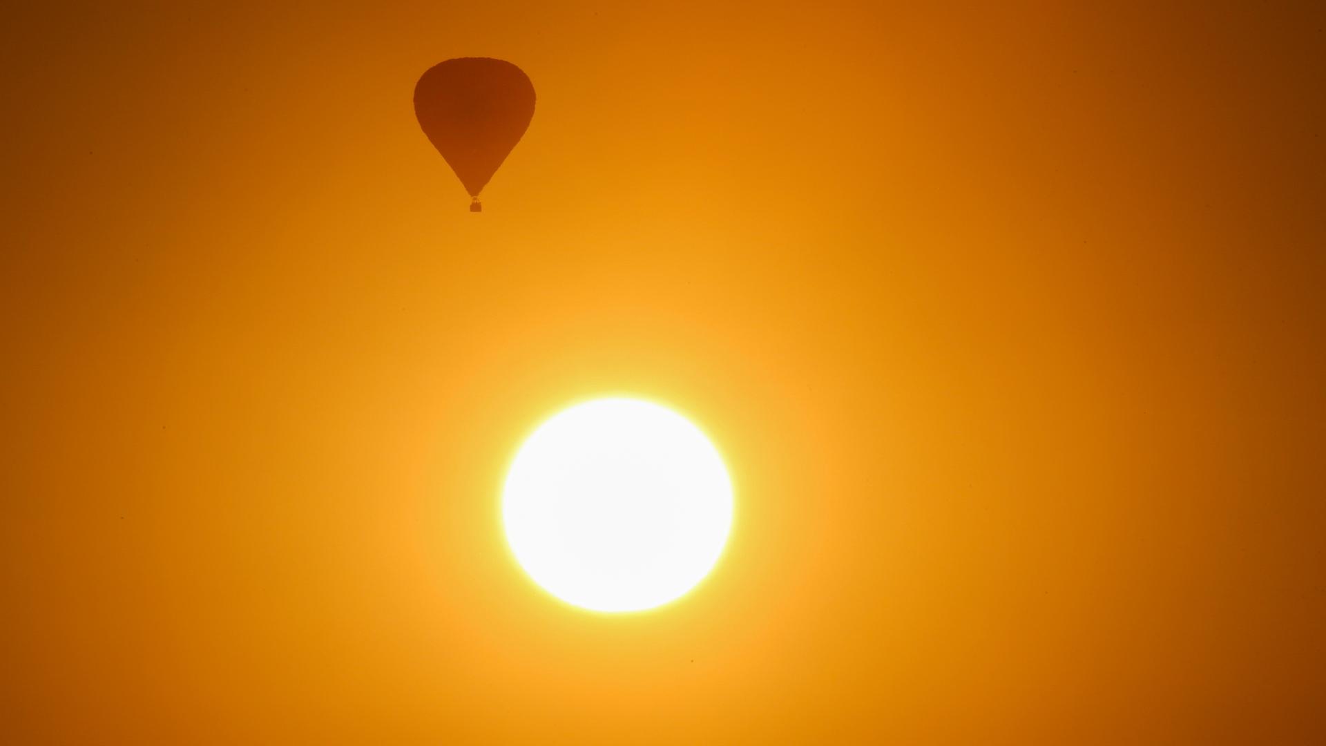 Ein Ballon fliegt im Sonnenaufgang