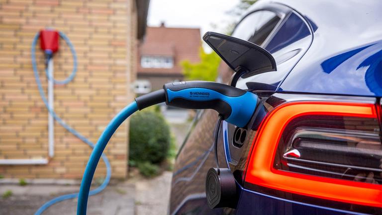 Ein E-Auto wird an einer Wallbox an einem Wohnhaus geladen.