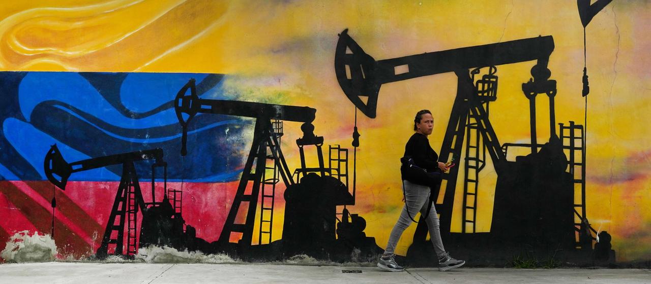 Ein Mann läuft an einer Mauer mit einem Graffiti vorbei, darauf Ölpumpen.