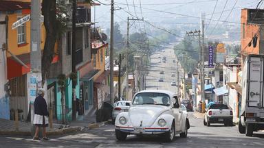 Ein Volkswagen Käfer erklimmt die Spitze eines Hügels in einem Viertel von Mexiko-Stadt.