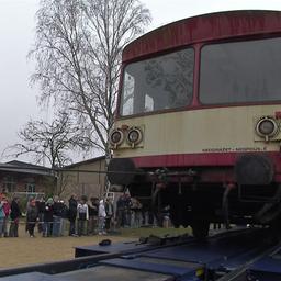 Schüler der Freien Waldorfschule Görlitz verfolgen, wie ein ausgedienter Eisenbahnwaggon von einem Tieflader auf ihren Schulhof entladen wird