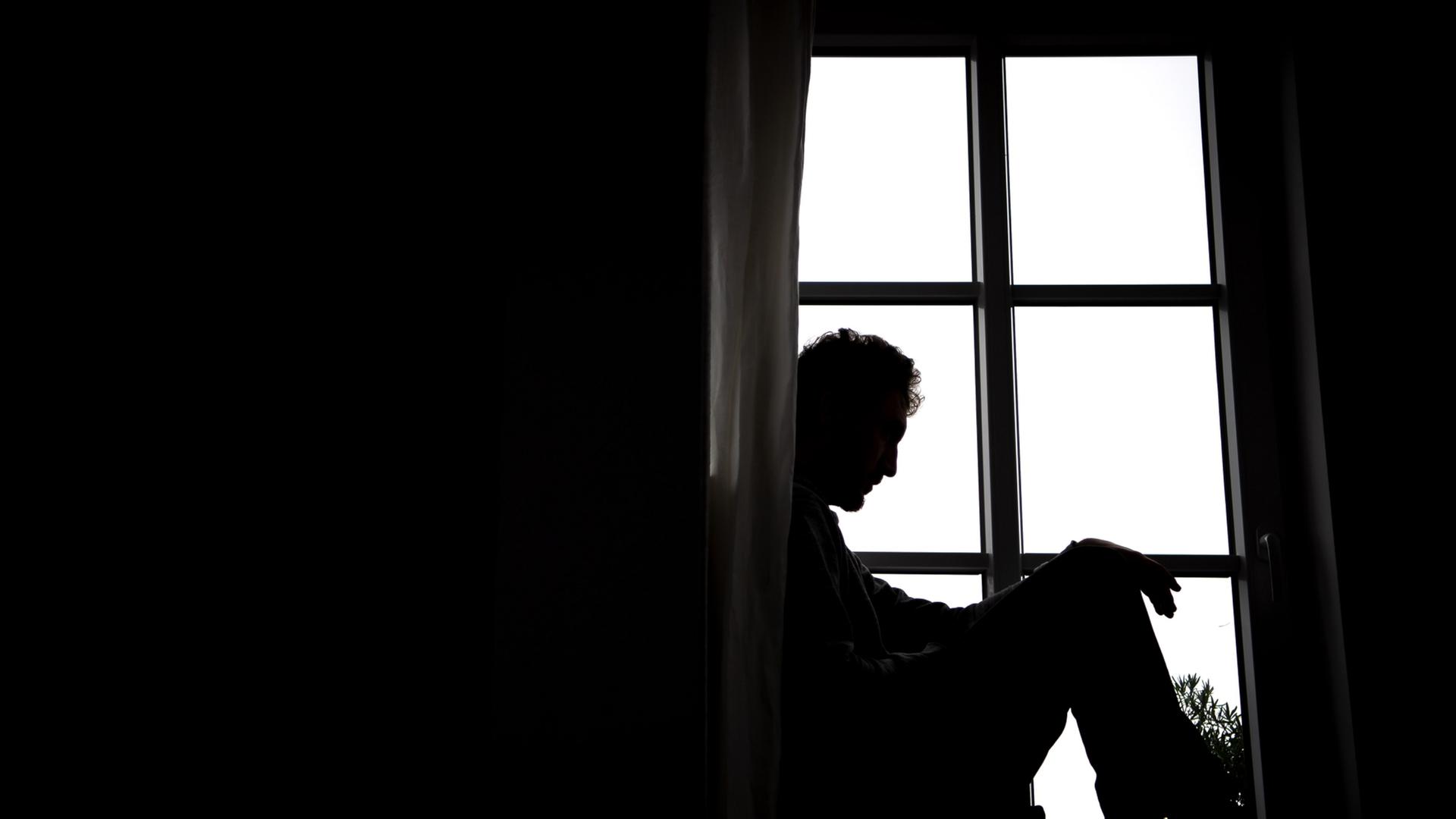 Ein Mann sitzt auf einer Fensterbank. | dpa