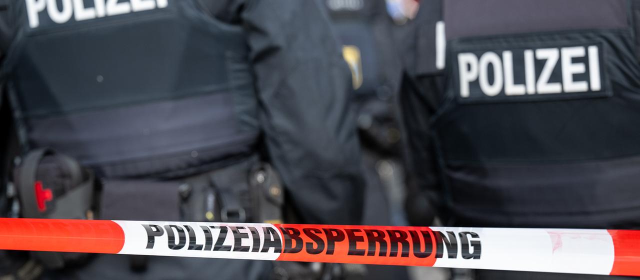 Polizisten hinter einem Absperrband (Mottobild)